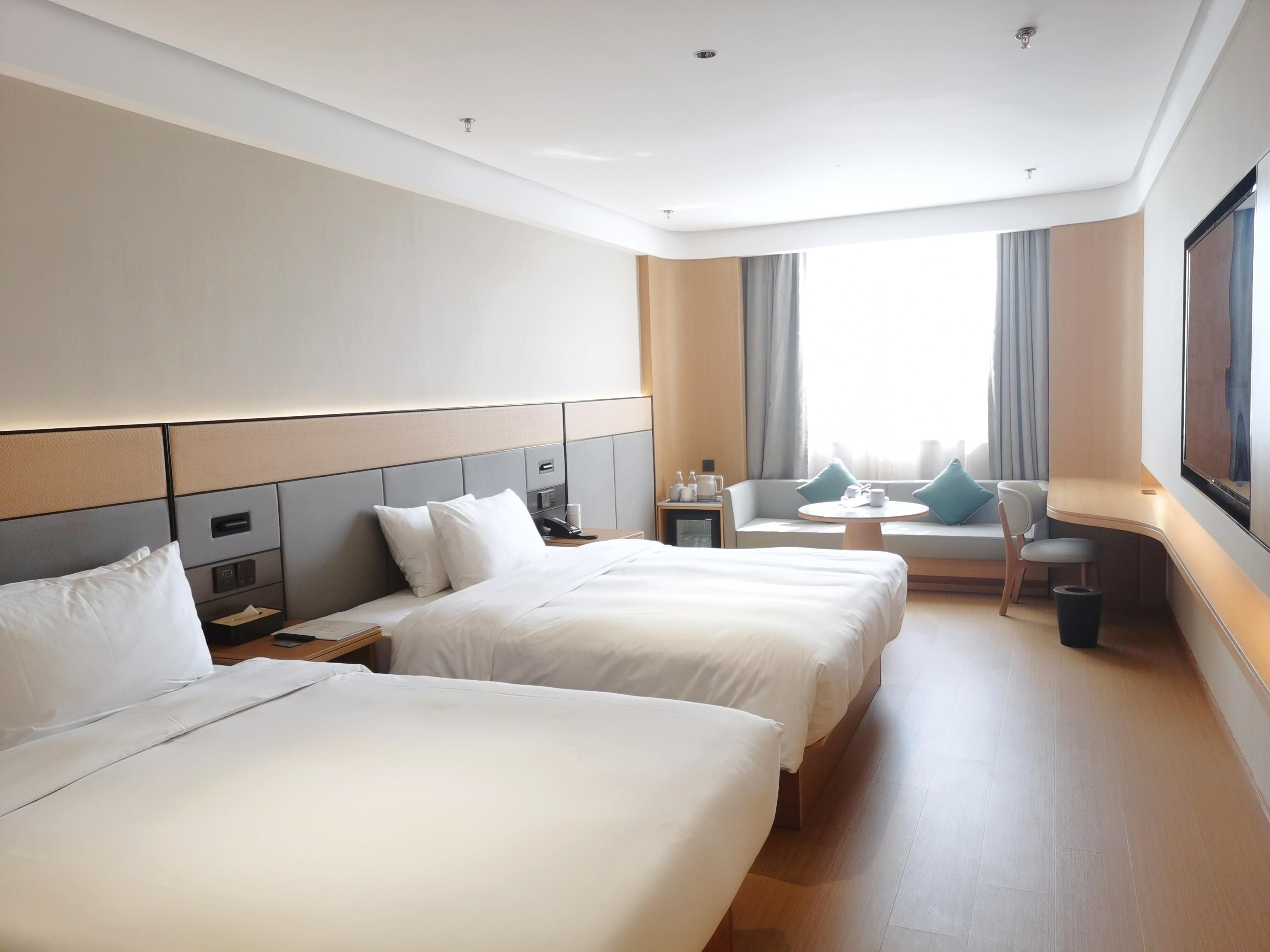 Habitación de hotel con dos camas, un sofá, una mesita y un televisor.
