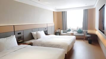 Habitación de hotel con dos camas, un sofá, una mesita y un televisor.