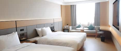 Habitación de hotel con dos camas, un sofá, una mesita y un televisor.