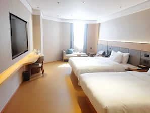 Ett hotellrum med två sängar, ett skrivbord med en stol, en TV och ett fönster med gardiner.