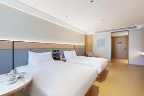 Ett hotellrum med två sängar, ett skrivbord, en stol, en klocka och en dörr.