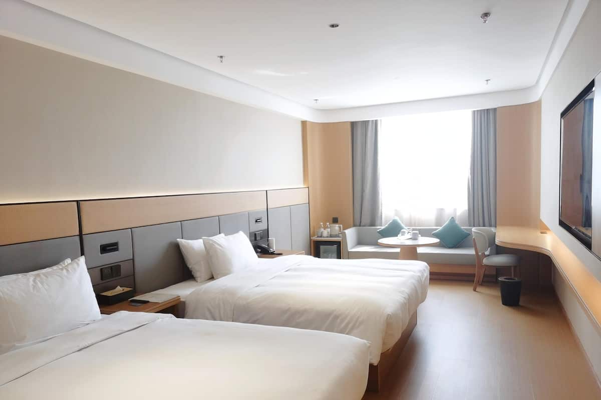 Habitación de hotel con dos camas, un sofá, una mesita y un televisor.