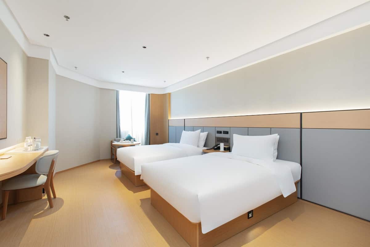 Una habitación de hotel moderna con dos camas, un escritorio y una silla.