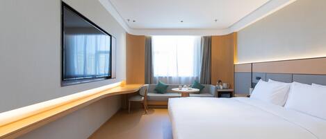 A hotel room with a bed, a desk, a chair, a small table, and a window.