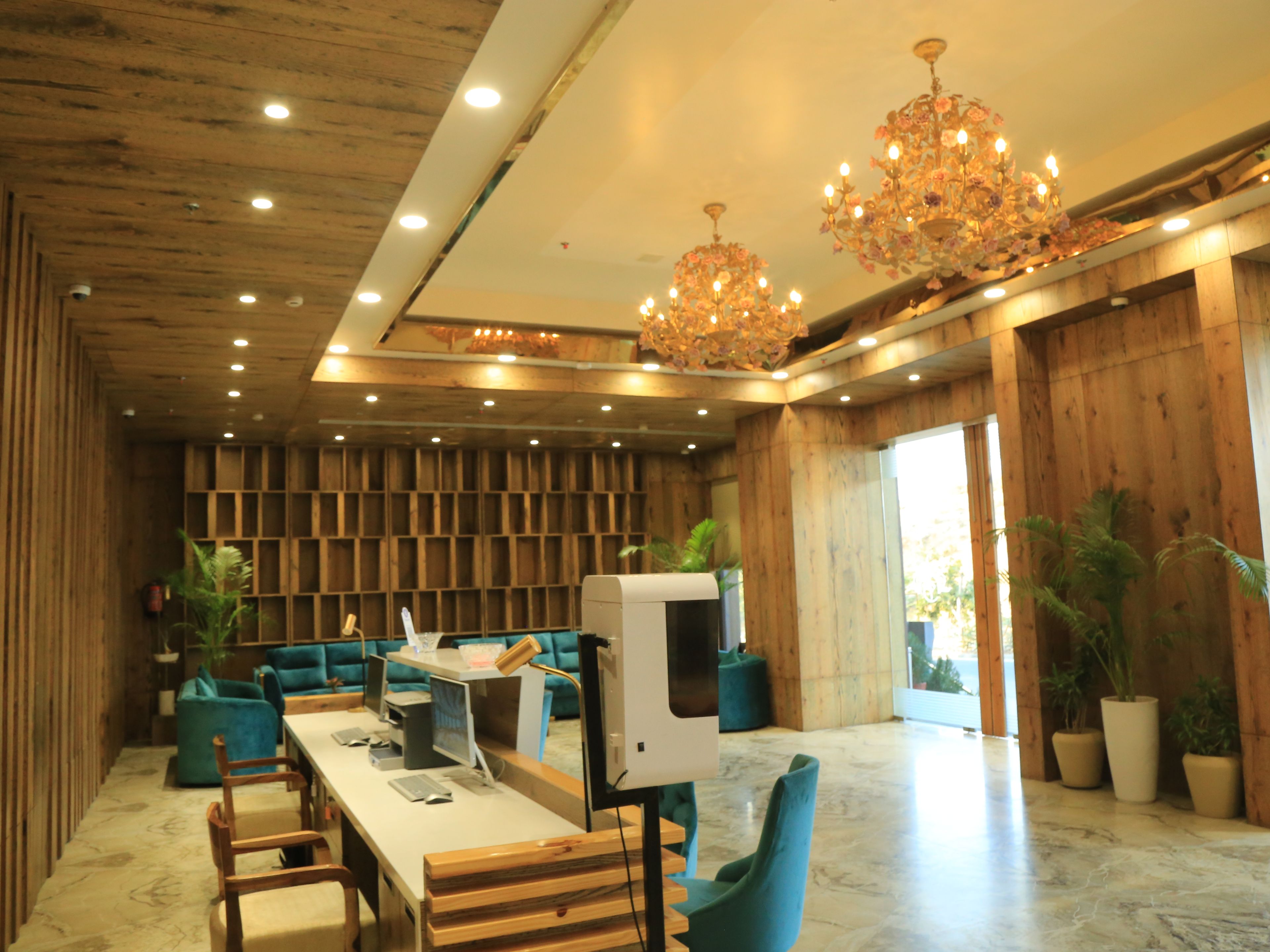 A modern interior with wooden paneling, a long table with chairs, a television, and a chandelier.