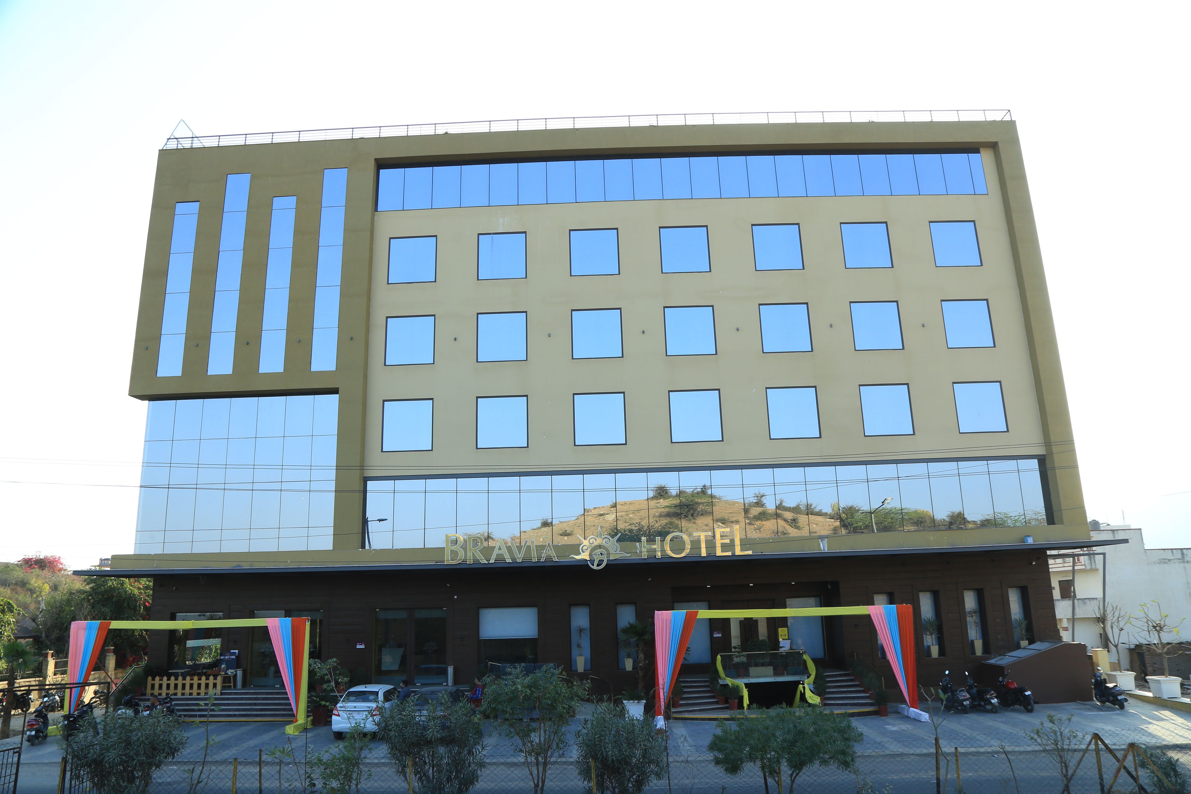 Un moderno edificio de hotel con fachada de vidrio, múltiples ventanas y un letrero que dice "BRAVIA HOTEL".