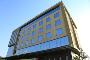 A multi-story hotel with a modern facade, large windows, and a prominent sign at the bottom. - Bravia Hotel Panchsheel (Ajmer)
