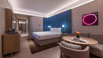 A modern hotel room with a bed, a sofa, a small table, and a TV.