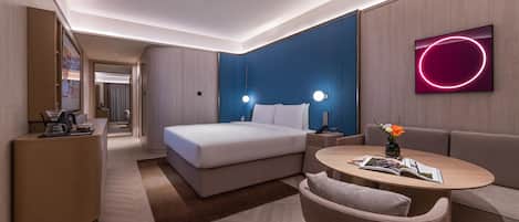 Une chambre d’hôtel moderne équipée d’un lit, d’un canapé, d’une petite table et d’un téléviseur.
