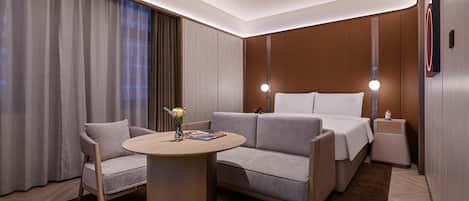 Une chambre d’hôtel moderne, équipée d’un canapé, d’une petite table, d’une table de chevet et d’un lit.