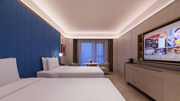 A hotel room with two beds, a TV, a small table with chairs, and a large window with curtains.