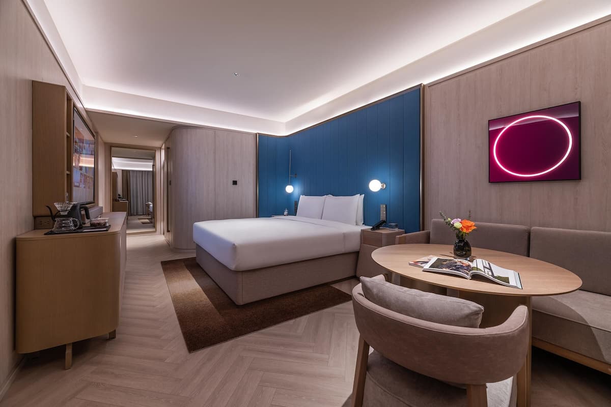 Une chambre d’hôtel moderne équipée d’un lit, d’un canapé, d’une petite table et d’un téléviseur.