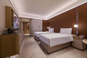 Une chambre d’hôtel avec deux lits, un bureau, un miroir et un téléviseur fixé au mur.