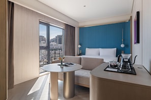 Una habitación de hotel moderna con un ventanal grande, un sofá, una mesa redonda y una zona de café.