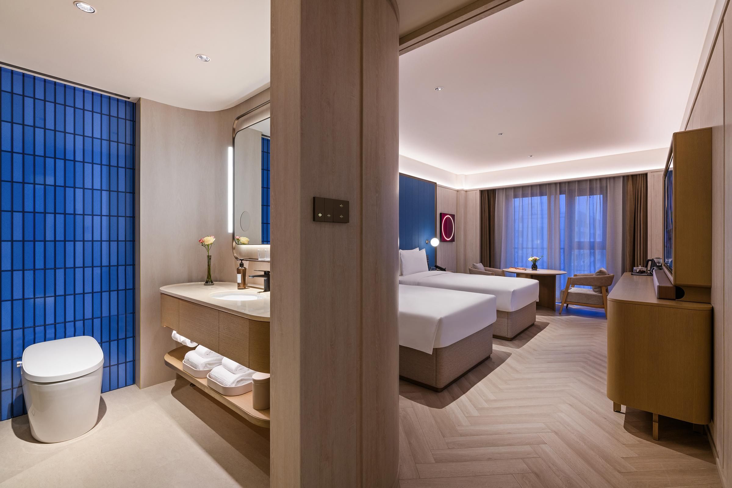A hotel room with a bathroom, a bed, a desk, and a chair.