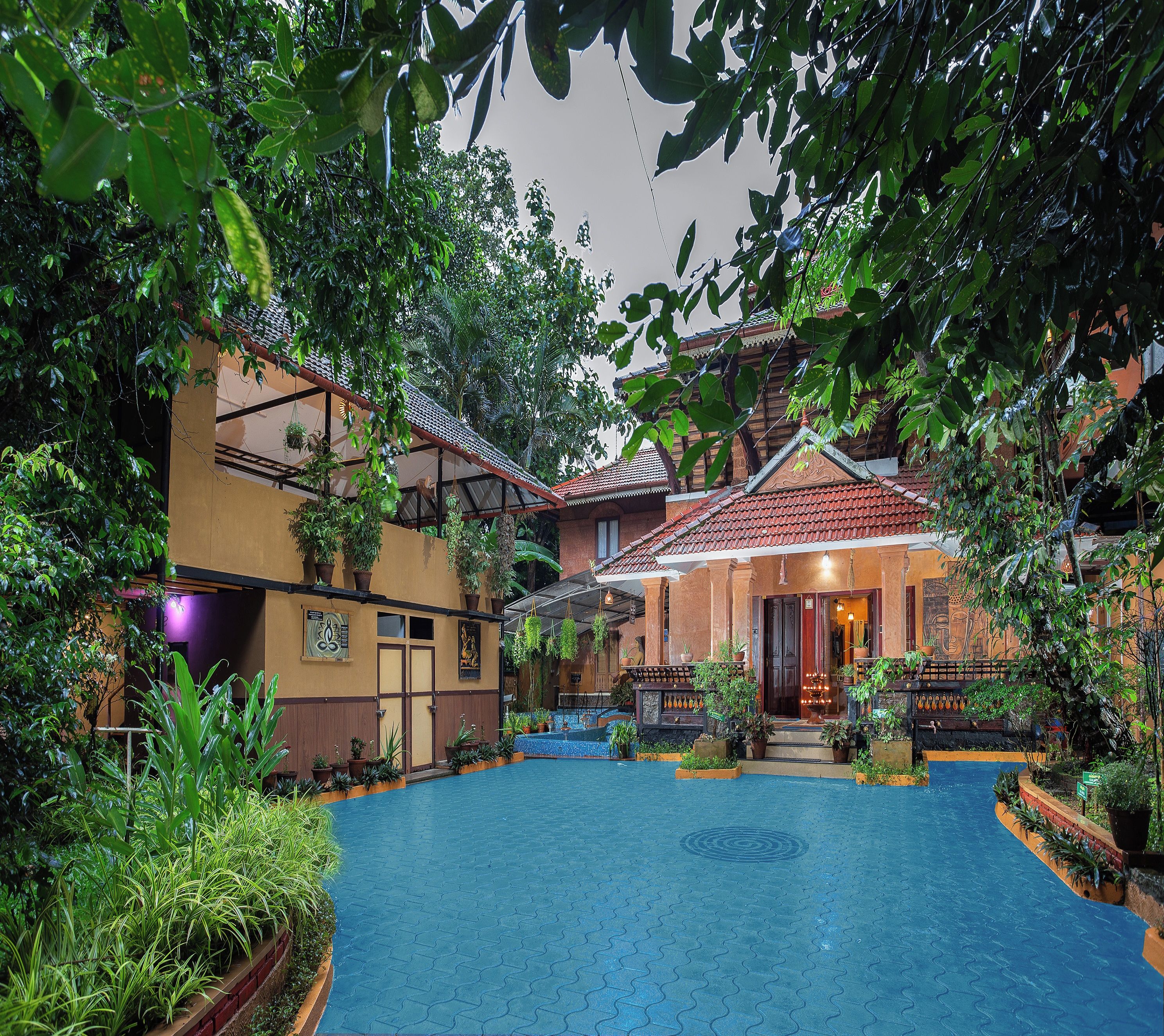 A courtyard with a pool, potted plants, and a traditional building with a tiled roof.