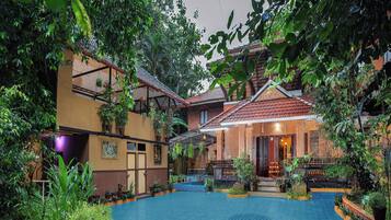 A courtyard with a pool, potted plants, and a traditional building with a tiled roof.