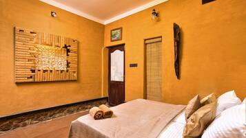 Quarto de hotel com cama, uma obra de arte na parede, porta e janela com persianas.