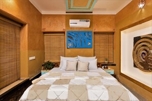 A bedroom with a bed, nightstands, a wall-mounted air conditioner, and a decorative wall piece. - Munkudil Ayurveda Yoga Retreat (Kothamangalam)