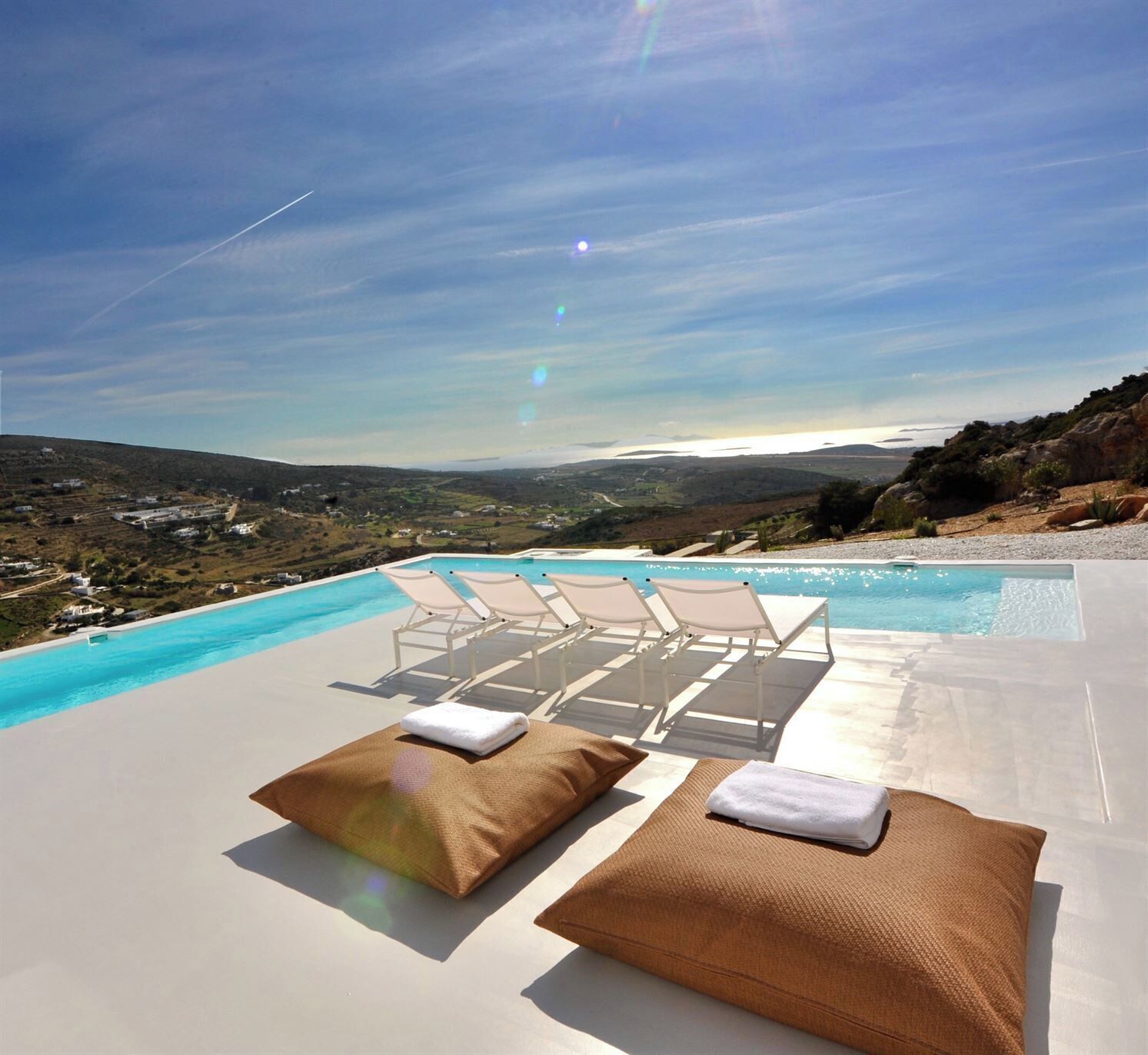 A poolside area with lounge chairs and towels, overlooking a scenic landscape.