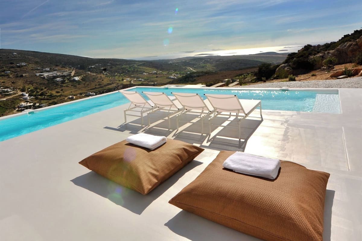 A poolside area with lounge chairs and towels, overlooking a scenic landscape.