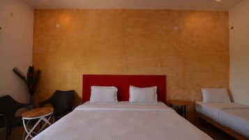 A hotel room with a large bed, two bedside tables, a small round table, and two chairs.