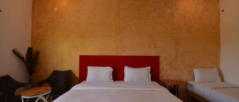 A hotel room with a large bed, two bedside tables, a small round table, and two chairs.