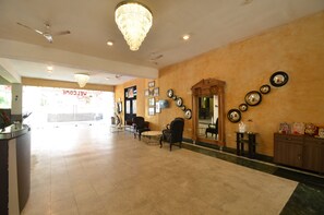 A hotel lobby with a reception desk, seating area, chandeliers, wall-mounted mirrors, and framed decorations. - Hotel Royal Casa (Abu Road)