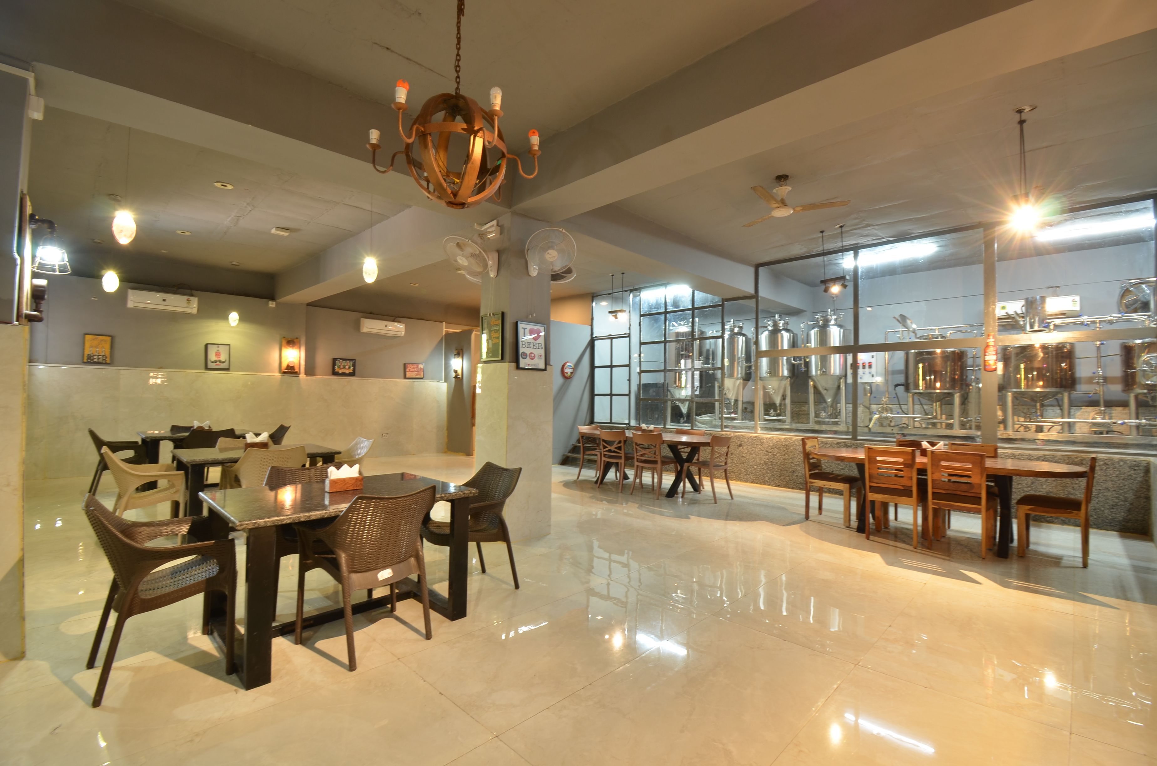A restaurant with multiple dining tables and chairs, a chandelier, ceiling fans, and large windows.