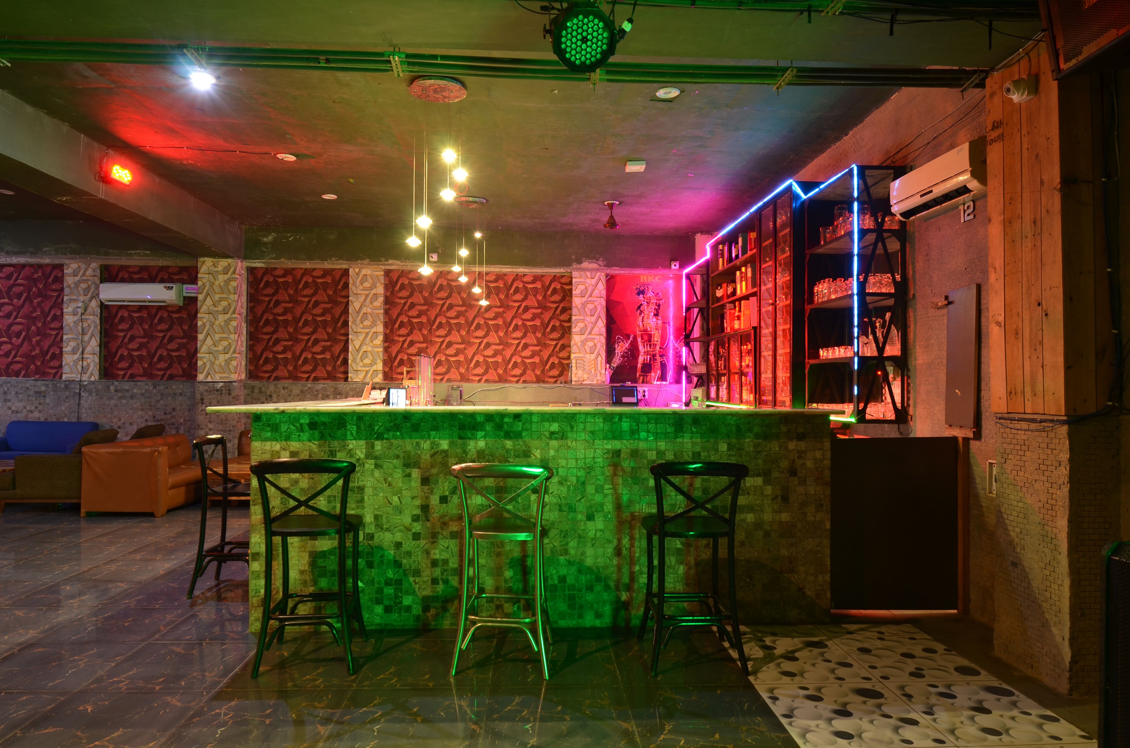 A bar area with a counter, stools, and shelves with bottles.