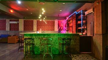 A bar area with a counter, stools, and shelves with bottles.