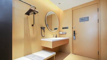 Un baño moderno con tocador de madera, un banco, un espejo, un perchero y una puerta con un letrero.