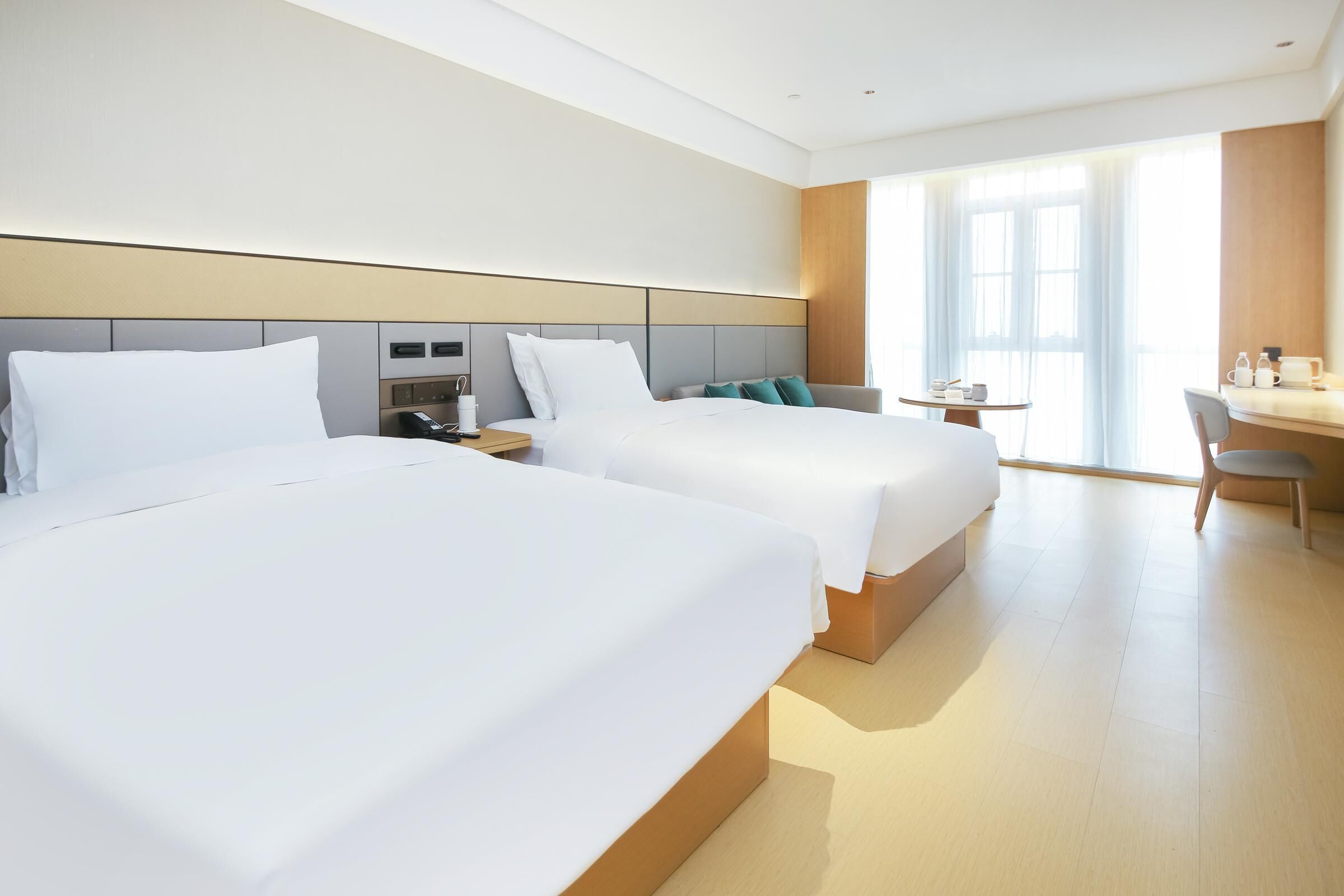 A hotel room with two beds, a desk, and a chair.