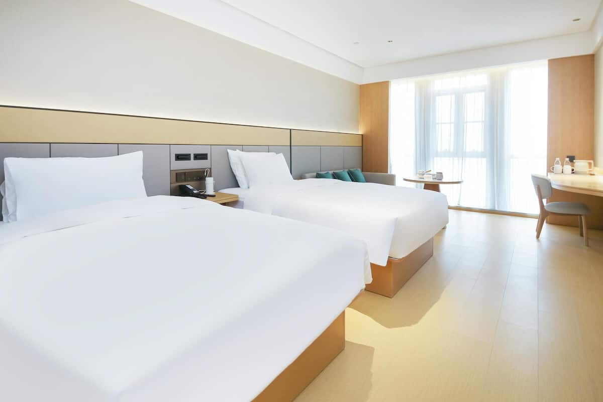 A hotel room with two beds, a desk, and a chair.
