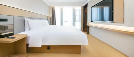 Quarto de hotel com cama, mesa de cabeceira, televisão e janela com cortinas.