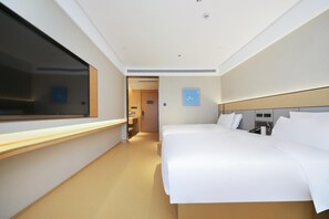 Hotellihuone, jossa on suuri sänky, yöpöytä, ikkuna ja ovi, joka johtaa käytävään.