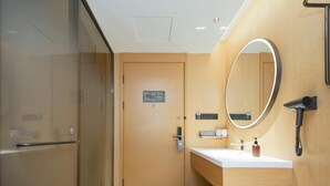 Ein modernes Badezimmer mit einer Duschkabine aus Glas, einem Holzwaschtisch mit Spiegel und einem Handtuchhalter.