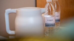 Ein weißer Krug und zwei Wasserflaschen mit Etiketten auf einer Oberfläche.