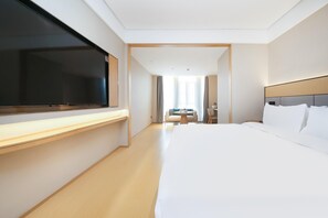 A hotel room with a large bed, a flat-screen TV, a desk, a chair, and a small table. - Ji Hotel Wuhan Optics Valley Biocity Tongji Hospit (Xianning)