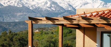 Edificio de piedra con una pérgola de madera y vista a la montaña.