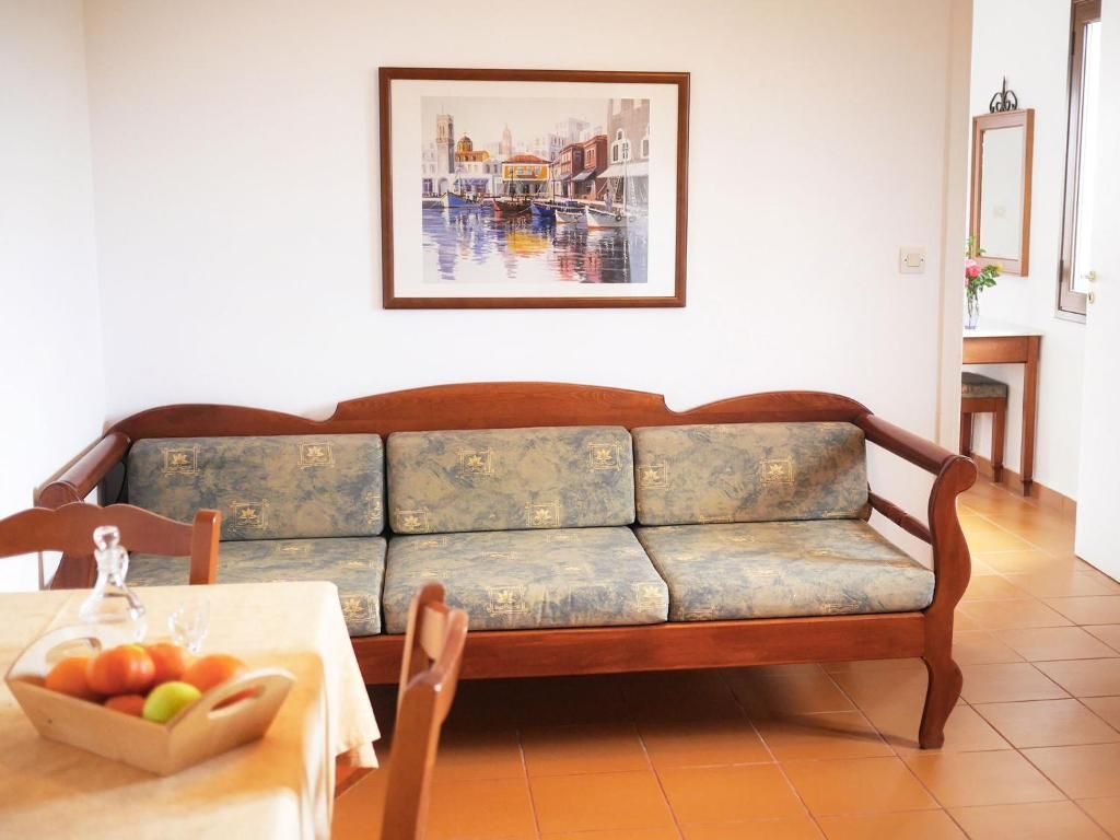 Una sala de estar con un sofá, una mesa con frutero y un cuadro enmarcado en la pared.