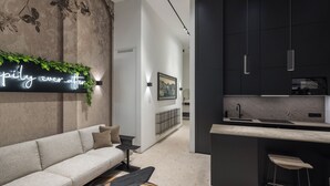 Ein modernes Interieur mit einer Couch, einer Neonreklame, einer Küchenzeile und einem Barhocker.