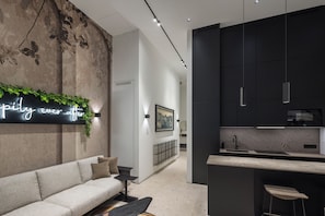 A modern interior with a sofa, a neon sign, a kitchen area, and a bar stool. - City Apartment Vienna Telegraph (Vienna)