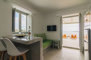 A modern kitchen with a dining area, a TV, and a view to the outside. - Olive Garden Luxury Resort (Paros)