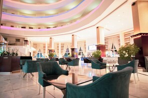 A spacious lobby with a curved ceiling, multiple seating areas, and a central staircase.