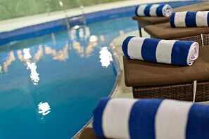 Uma área à beira da piscina com espreguiçadeiras e toalhas.