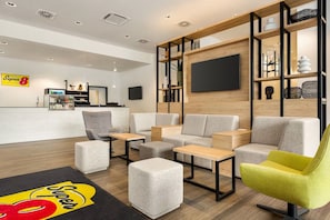 En moderne hotellobby med siddepladser, en bar og et tv.