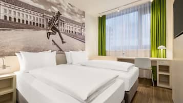 Ein Hotelzimmer mit einem Bett, einem Schreibtisch, einem Stuhl, einer Schreibtischlampe und einem großen Fenster mit grünen Vorhängen.