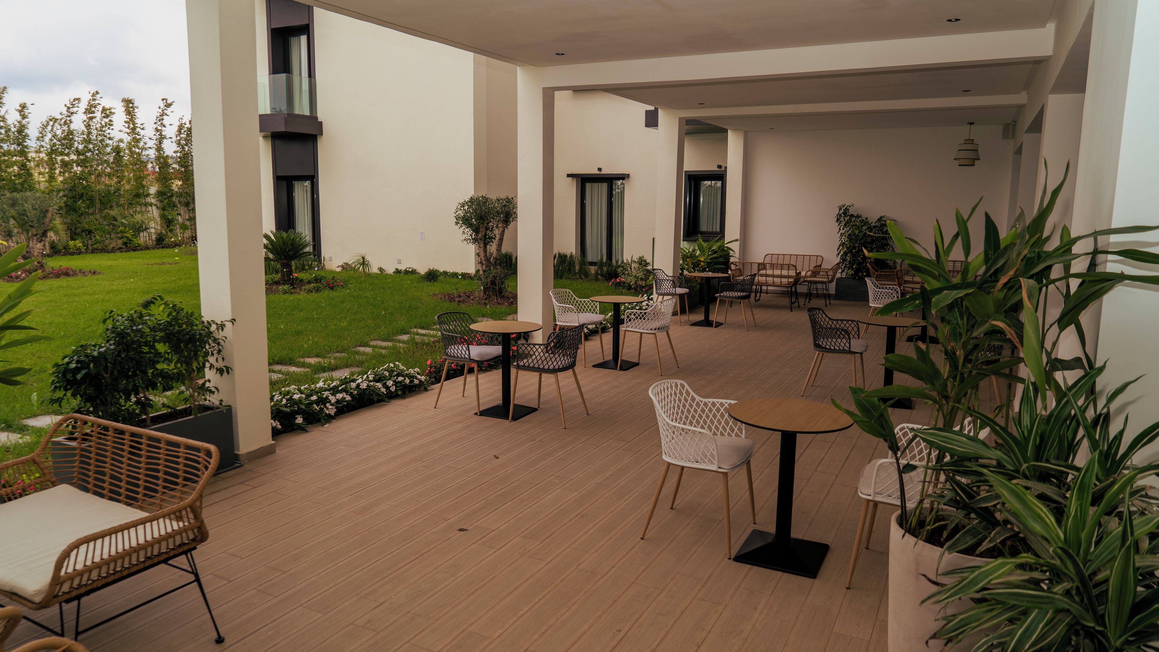 Un portico esterno coperto con tavoli e sedie, immerso nel verde e con vista su un giardino.