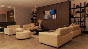 A modern hotel lobby with sofas, a coffee table, and a TV screen. - Hotel Ben Batouta (Hjar Ennhal)